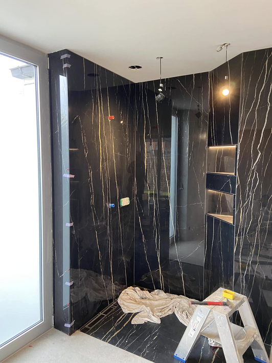 Salle de bain en marbre noir avec spots et niches éclairées