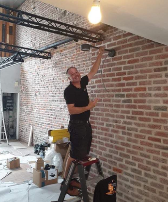 Électricien DWA intervenant sur un luminaire mural